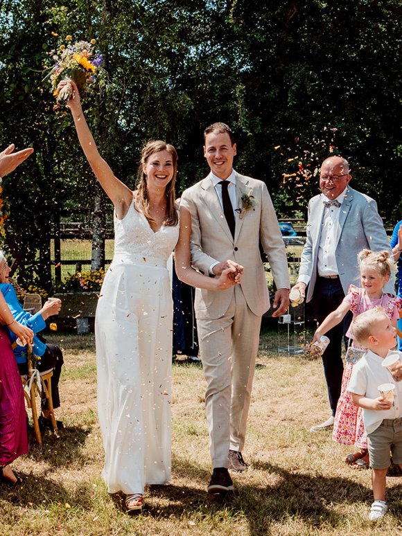 Bruidspaar hand in hand lopend door het gangpad na het einde van de ceremonie