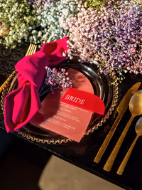 CLose up diner bord met gouden rand, roze acryl menu , roze acryl naamkaartje, roze servet, gipskruidtakje en gouden bestek