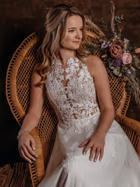 close up van bruid in een peacock chair die versierd is met bloemen