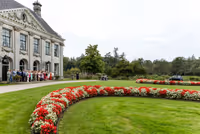 Bruidspaar komt aanrijden, gasten staan in haag voor trouwlocatie