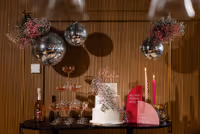 Foto van de taartafel met champagne toren versierd met gekleurde gipskruid bollen en discoballen