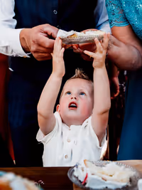 klein jongentje wat met de handjes omhoog staat en heel graag het schoteltje met taart boven zijn hoofd wil pakken