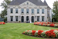 Bruidspaar voor Trouwlocatie, staand bij trouwauto